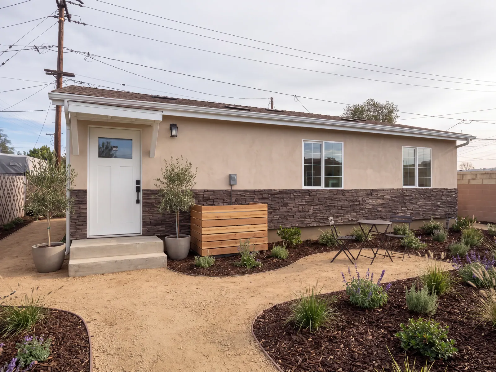 Detached ADU with tan stucco, stone wainscot, a white entry door and drought-tolerant planting
