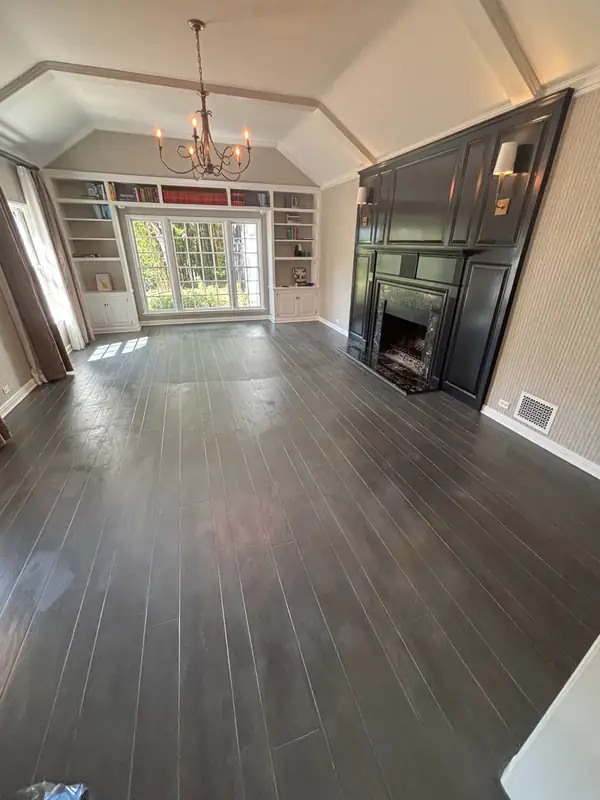 The living room with dark espresso floors and a black fireplace surround