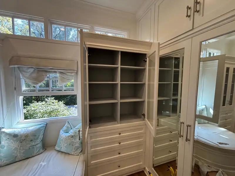 Closet built-ins with open shelving beside a window seat