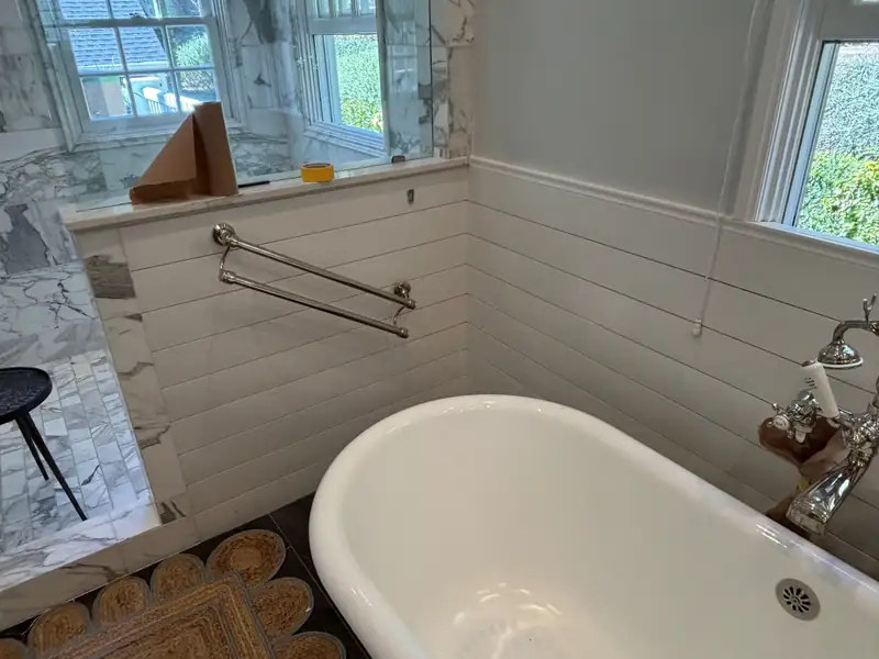Clawfoot tub set below a window with wainscot paneling