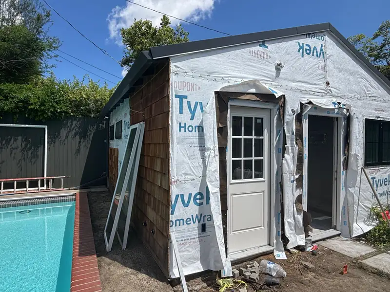The studio wrapped in house wrap with new doors installed beside the pool