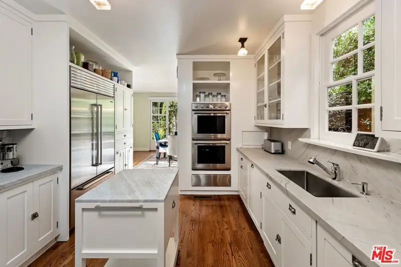 The galley kitchen before the remodel: white cabinetry, marble counters and stainless appliances