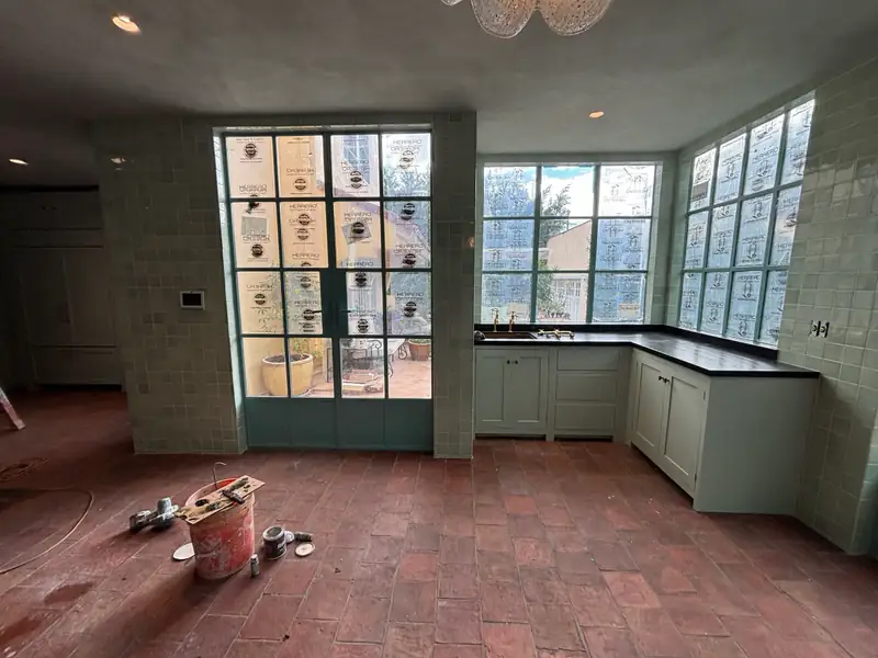 Painted cabinetry with dark counters set along the tiled walls
