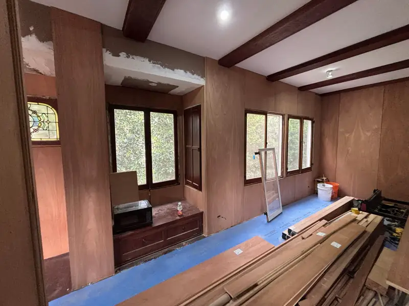 Wood-paneled room with beamed ceiling and a stained-glass window as demolition began