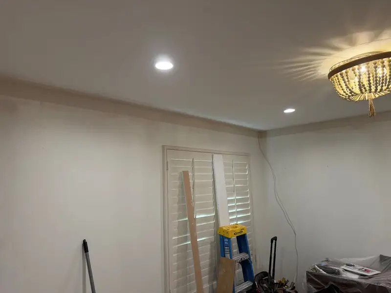 The study before the remodel: white walls, plantation shutters and a beaded chandelier