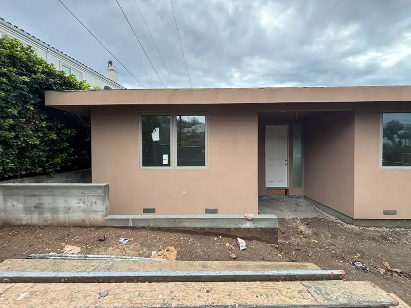 The new single-story home in smooth stucco with new windows, before landscaping