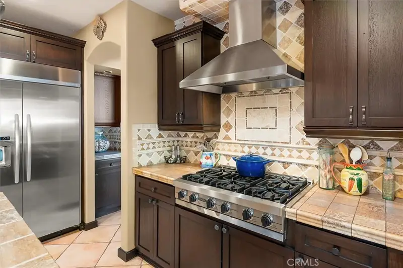 The kitchen before the remodel: dark cabinetry, a stainless hood and busy tile