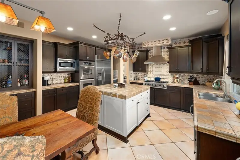 The old island and dark cabinets, with iron fixtures overhead