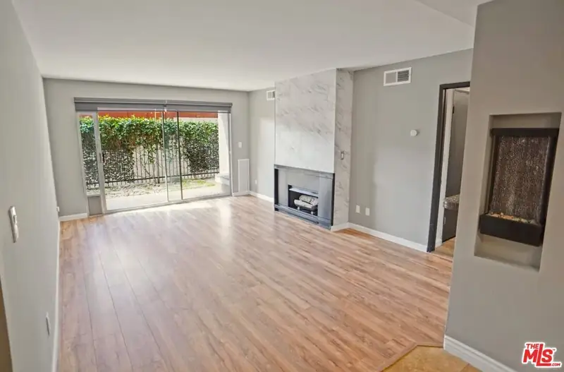 The original living room with laminate floors and a plain fireplace surround