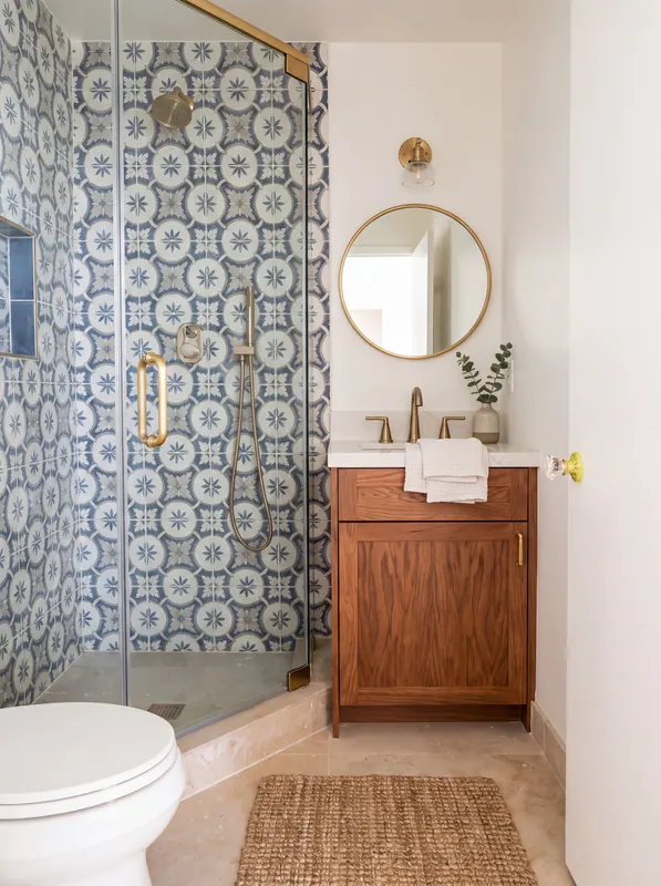 Bath with a blue-and-white encaustic tile shower, frameless glass with brass hardware and a walnut vanity