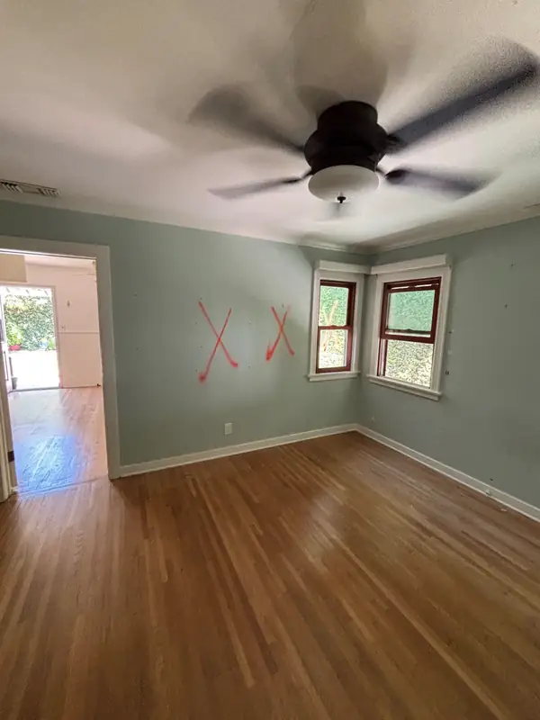 A bedroom marked up for demolition, with dated paint and trim