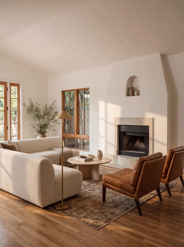 Living room with a sculpted plaster fireplace, arched niche, limestone surround and stained wood divided-lite windows