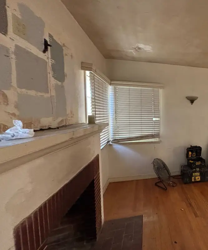 Corner of the original living room with its brick fireplace and wood floors
