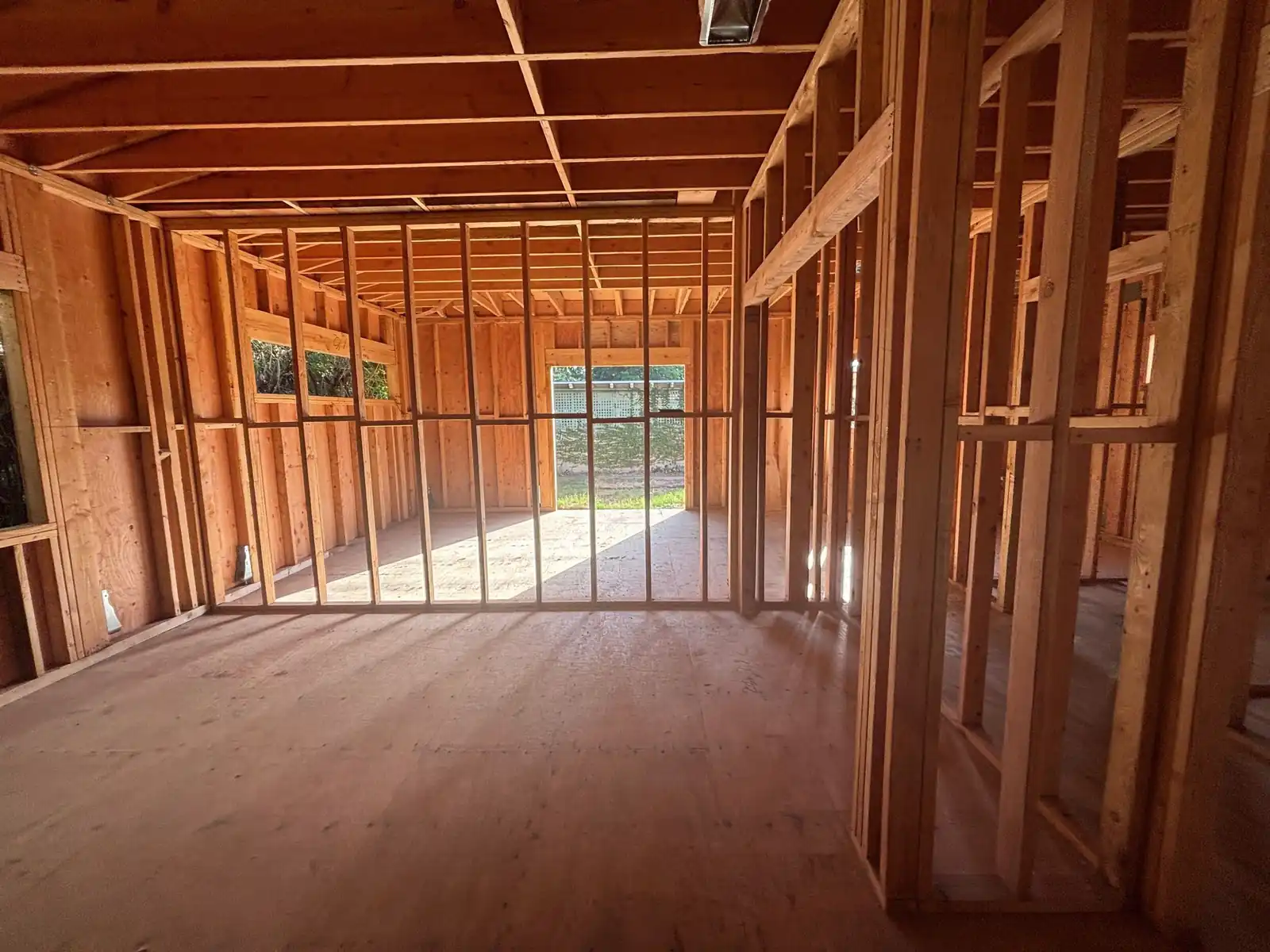 Inside the new home in framing: open stud walls and window openings with afternoon light