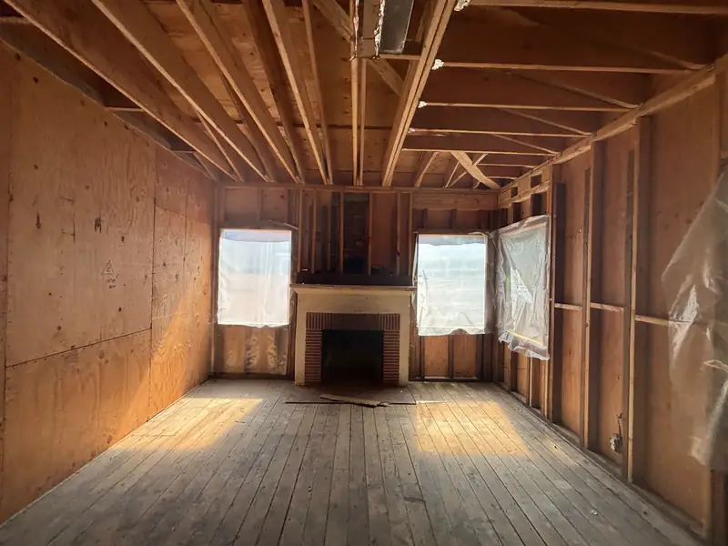 The framed living room around the fireplace, sheathing on and windows cut in