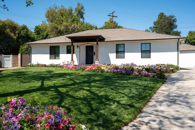 Single-story home with white stucco, black-framed windows and a timber entry porch