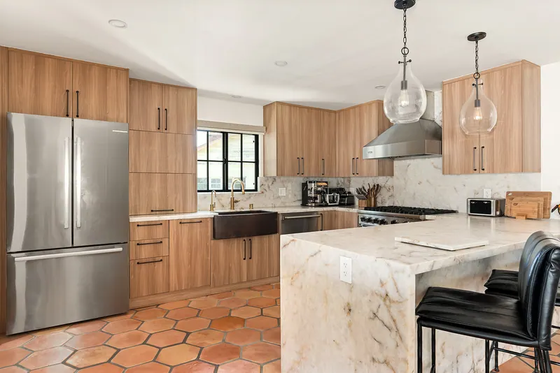 Kitchen peninsula with a waterfall counter, glass pendants and counter stools