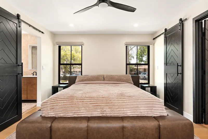 Primary bedroom with black sliding barn doors and black-framed windows