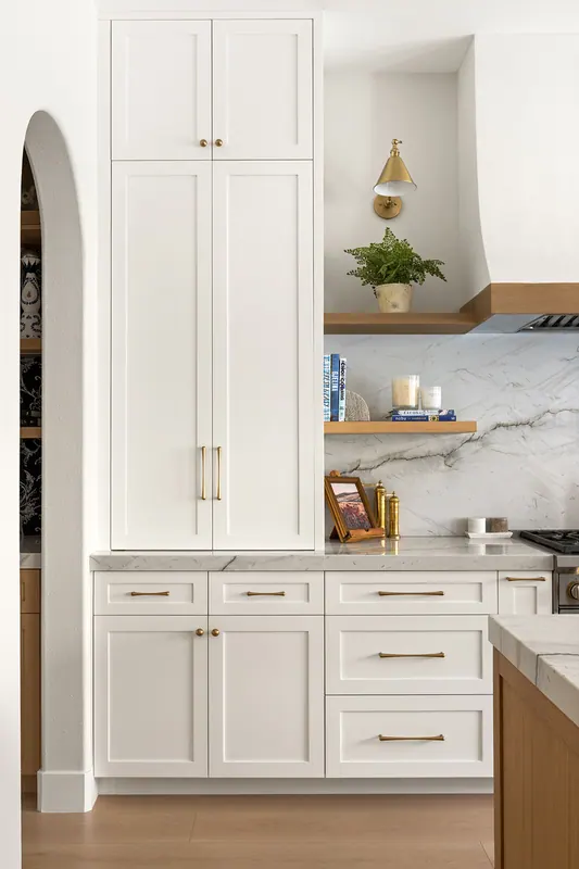 Tall white pantry cabinets beside an arched opening
