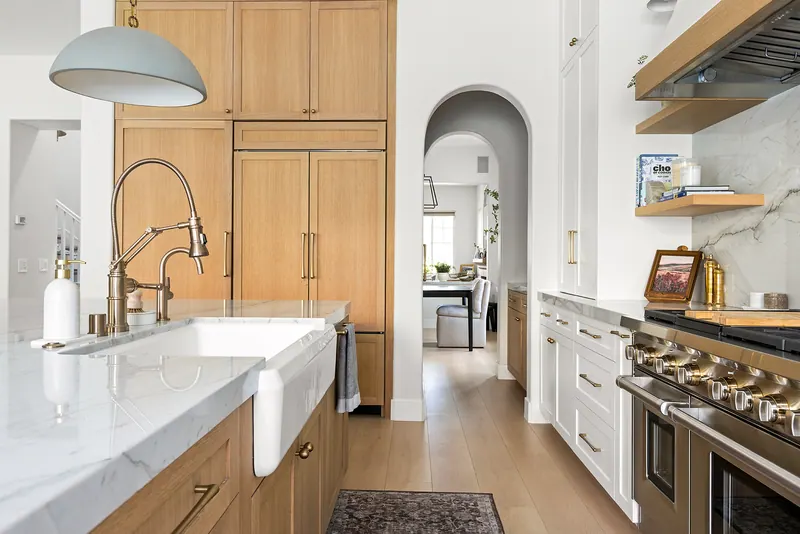 Farmhouse sink and bridge faucet in a stone-topped island