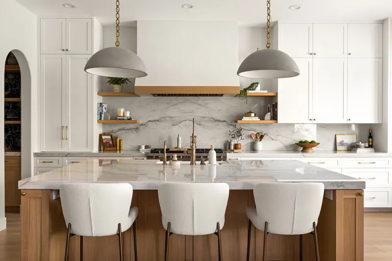 Symmetrical kitchen with plaster hood, stone backsplash and white oak island