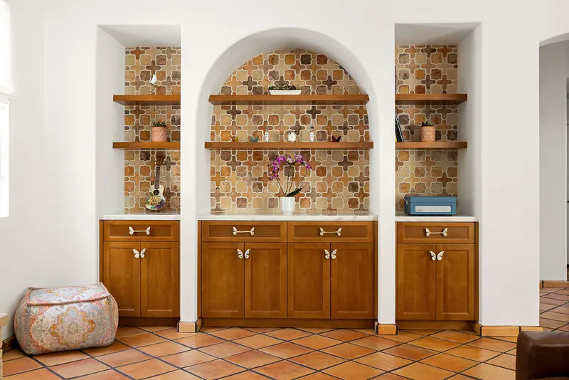 Arched niches lined with patterned tile, floating shelves and wood cabinets