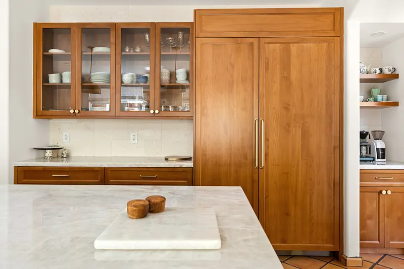 Glass-front upper cabinets beside a paneled refrigerator