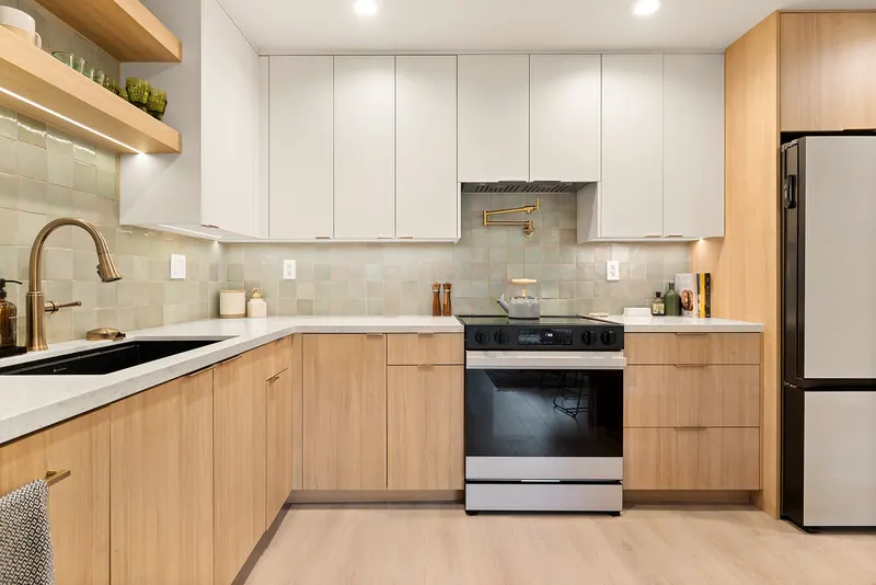 L-shaped kitchen with oak-tone cabinets, white uppers and a brass faucet
