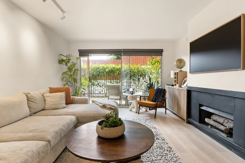Living room with a linear fireplace, wall-mounted TV and sliding doors to the patio