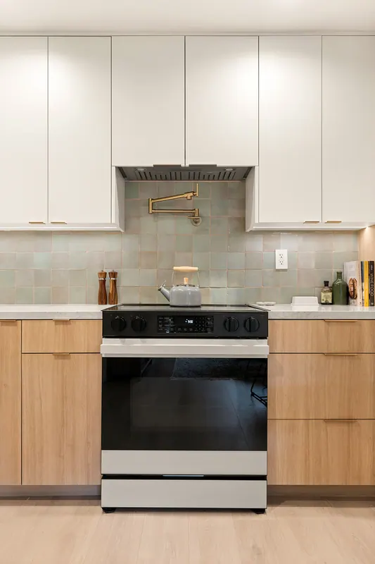 Range wall with glazed tile backsplash and white upper cabinets