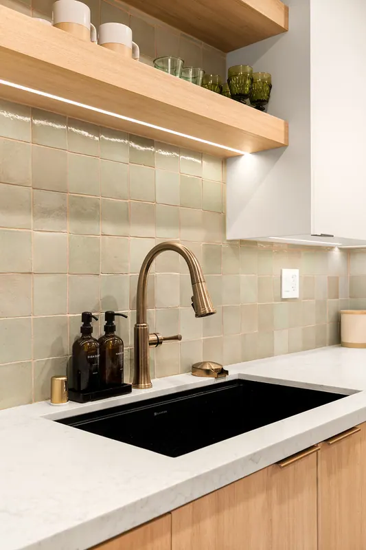 Undermount sink and brass faucet below floating oak shelves